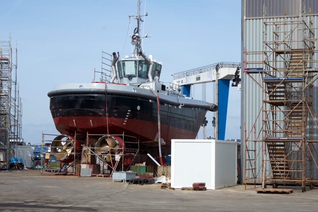 A large ship undergoing repairs in an industrial dockyard setting. Perfect for maritime industry themes.